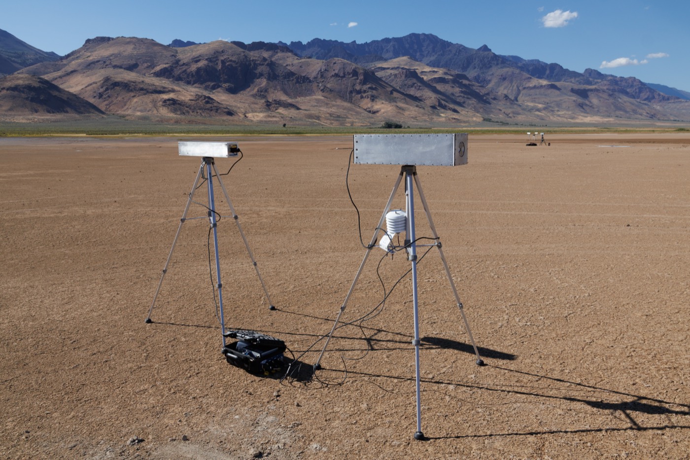 Close-up of the paired moderated and bare CRNS detector modules on tripods with weather sensor and data logger