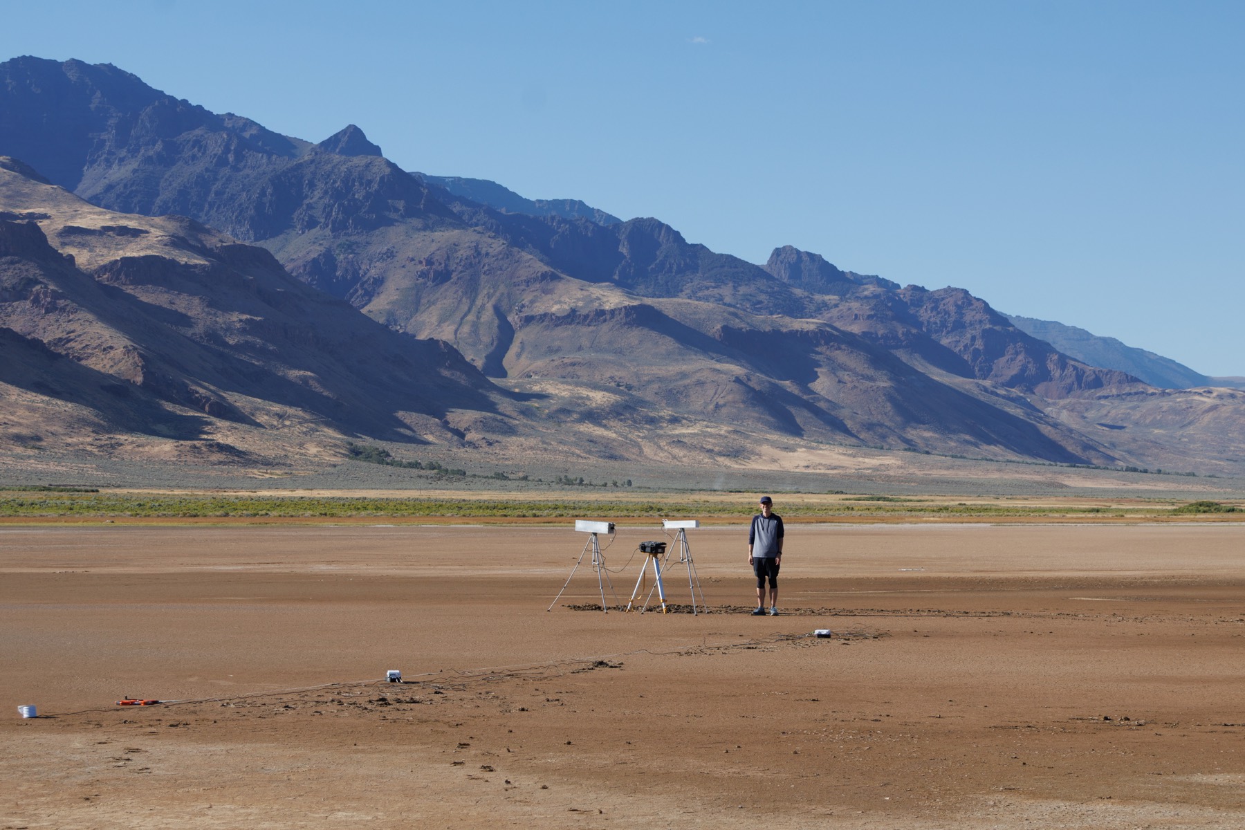 Paired cosmic-ray neutron sensors on tripods on the Alvord Playa, Oregon, with Steens Mountain in the background