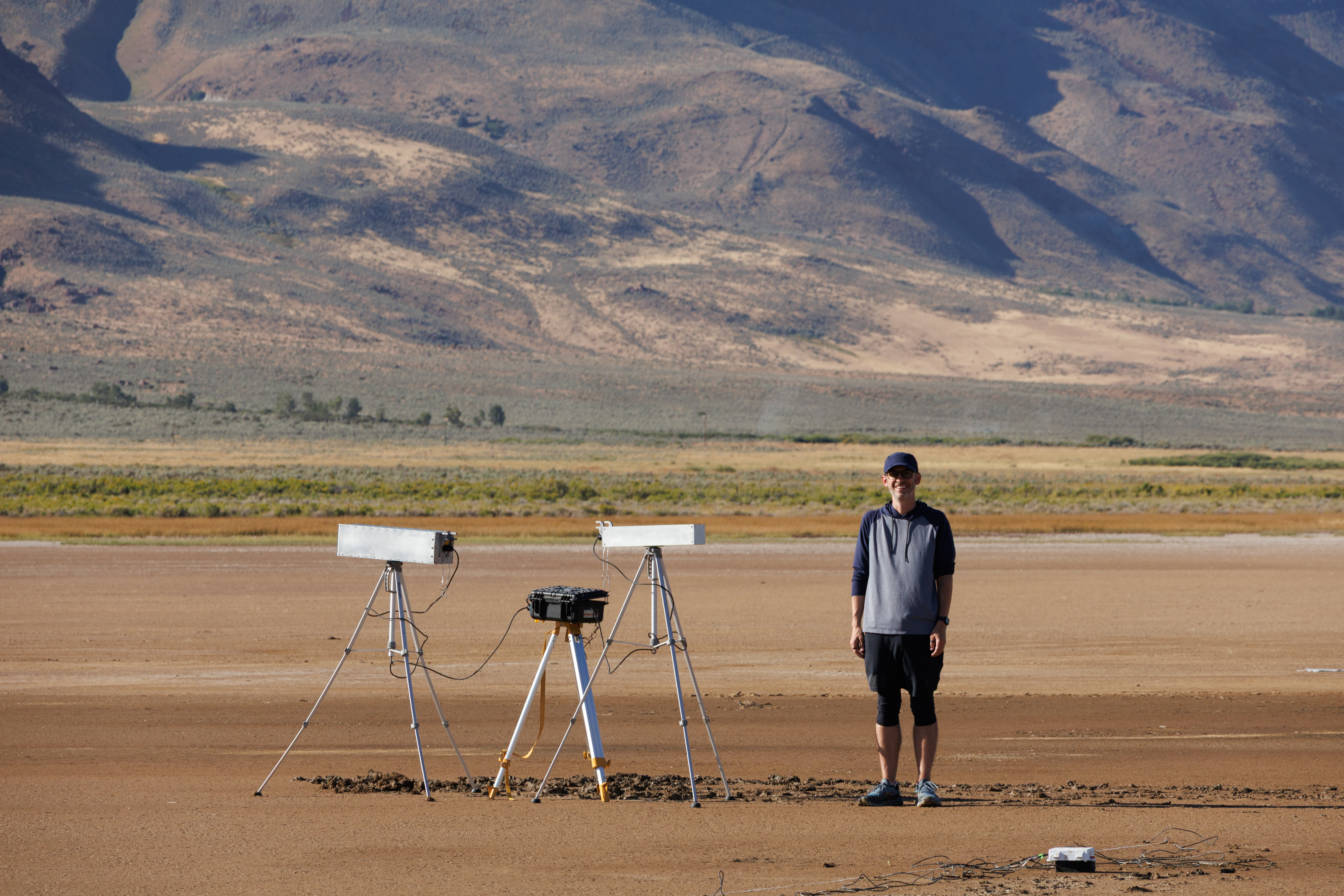 Craig Hardgrove next to tripod-mounted cosmic-ray neutron sensors on the Alvord Playa
