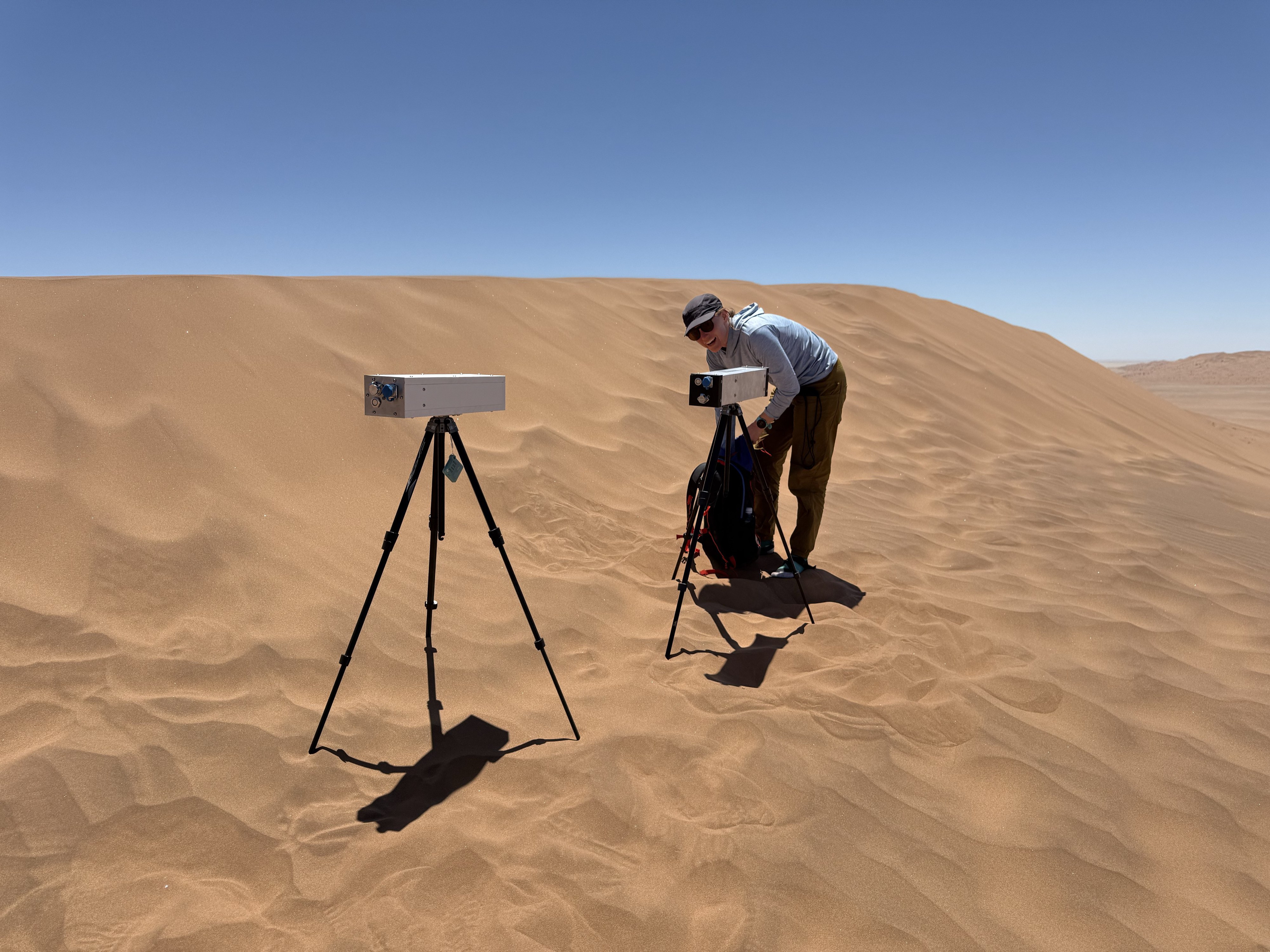 Craig Hardgrove deploying a cosmic-ray neutron sensor on a tripod on a Namib Desert dune